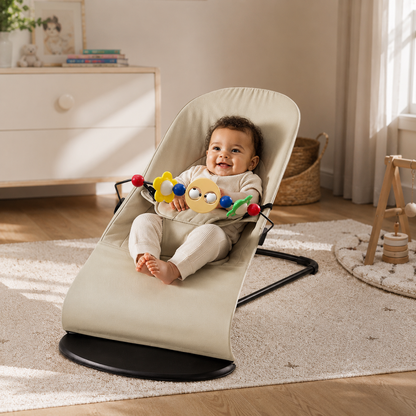 Baby sitting in a beige baby bouncer with colorful toys in a home setting.