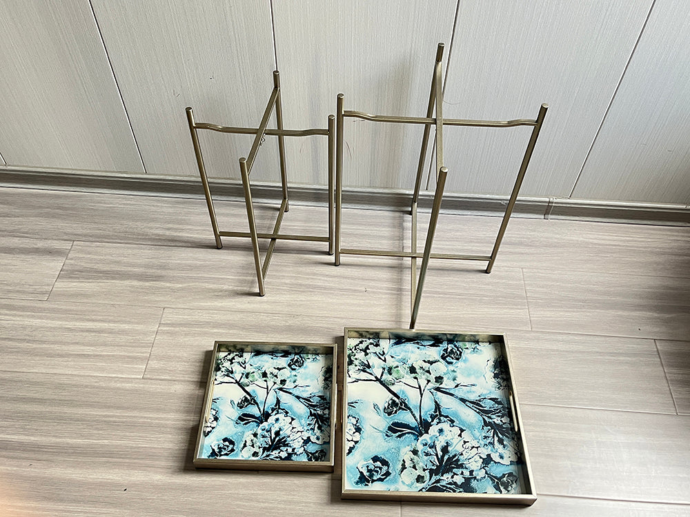 Set of 2 MSL Art Deco nesting side tables with gold floral marble effect square surfaces and sleek legs.